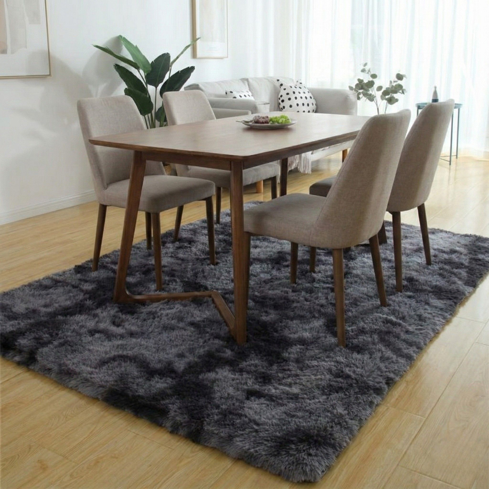 Donkergrijs hoogpolig vloerkleed van 160×230 cm onder een houten eettafel met vier stoelen.