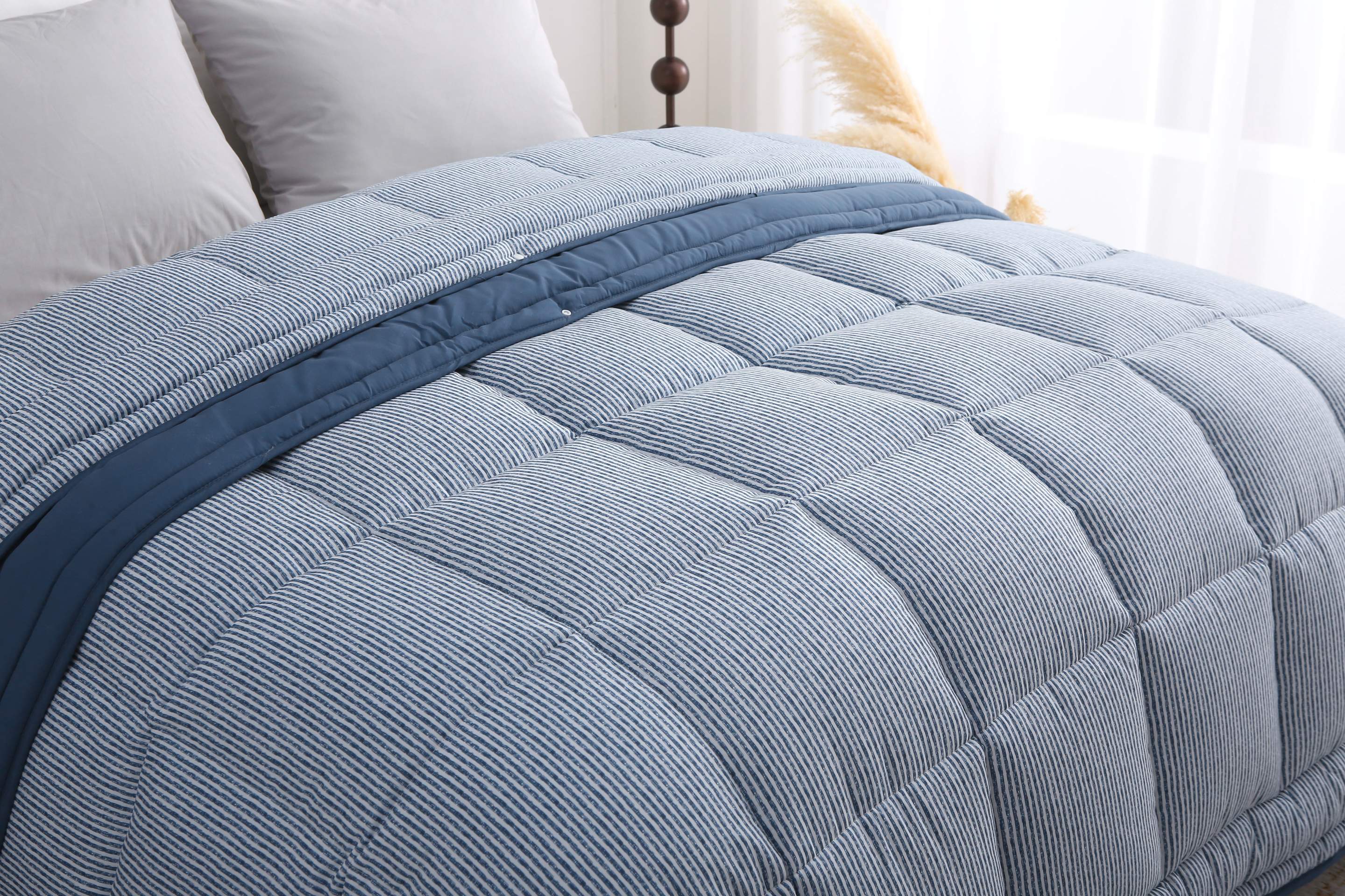 Close-up van het blauw-wit gestreepte 4-seizoenendekbed zonder overtrek, waarbij het dekbed deels is opengevouwen om de binnenzijde te tonen.