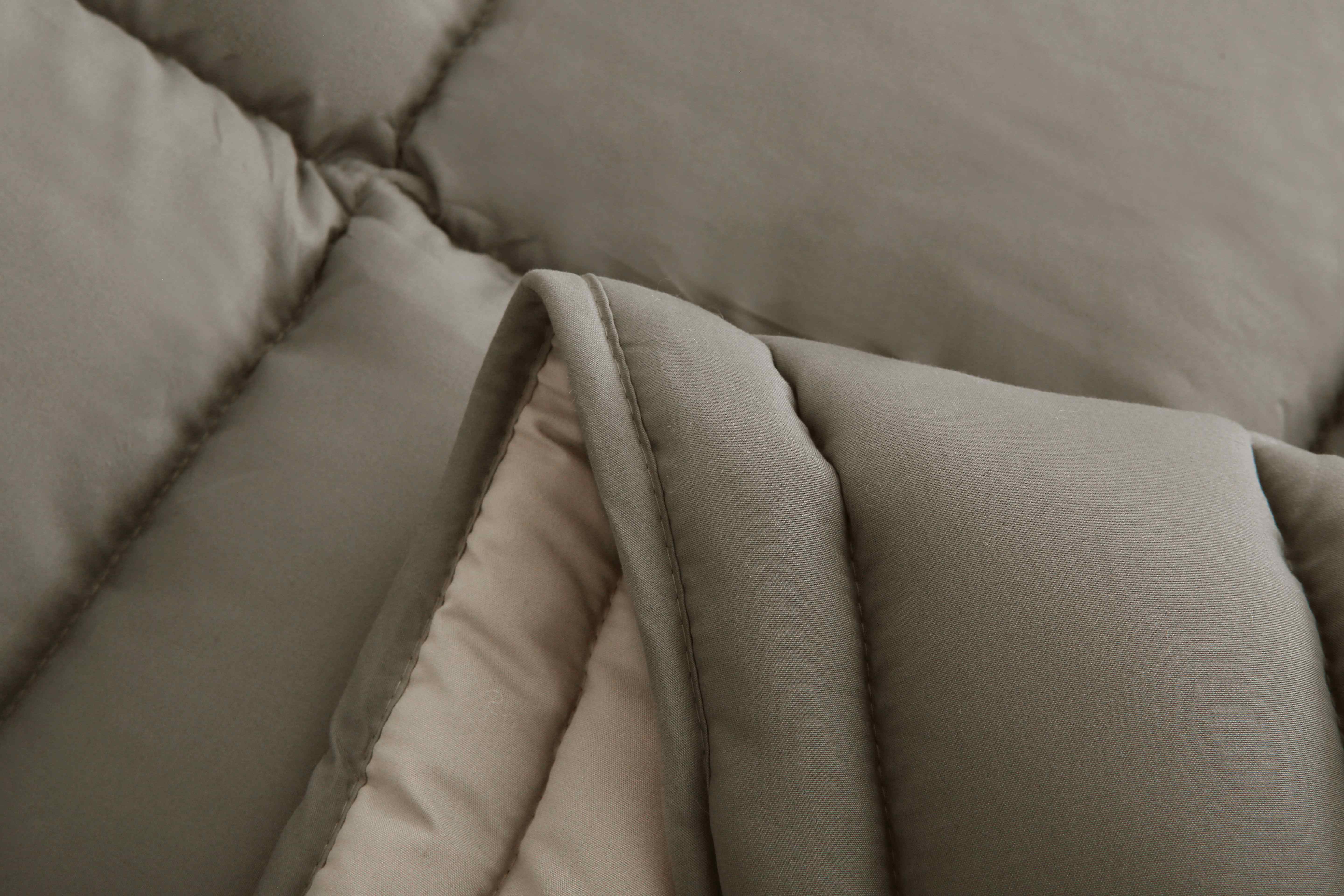 Close-up van de zachte microvezelstof van het taupe 4-seizoenen dekbed van Zorgmatras