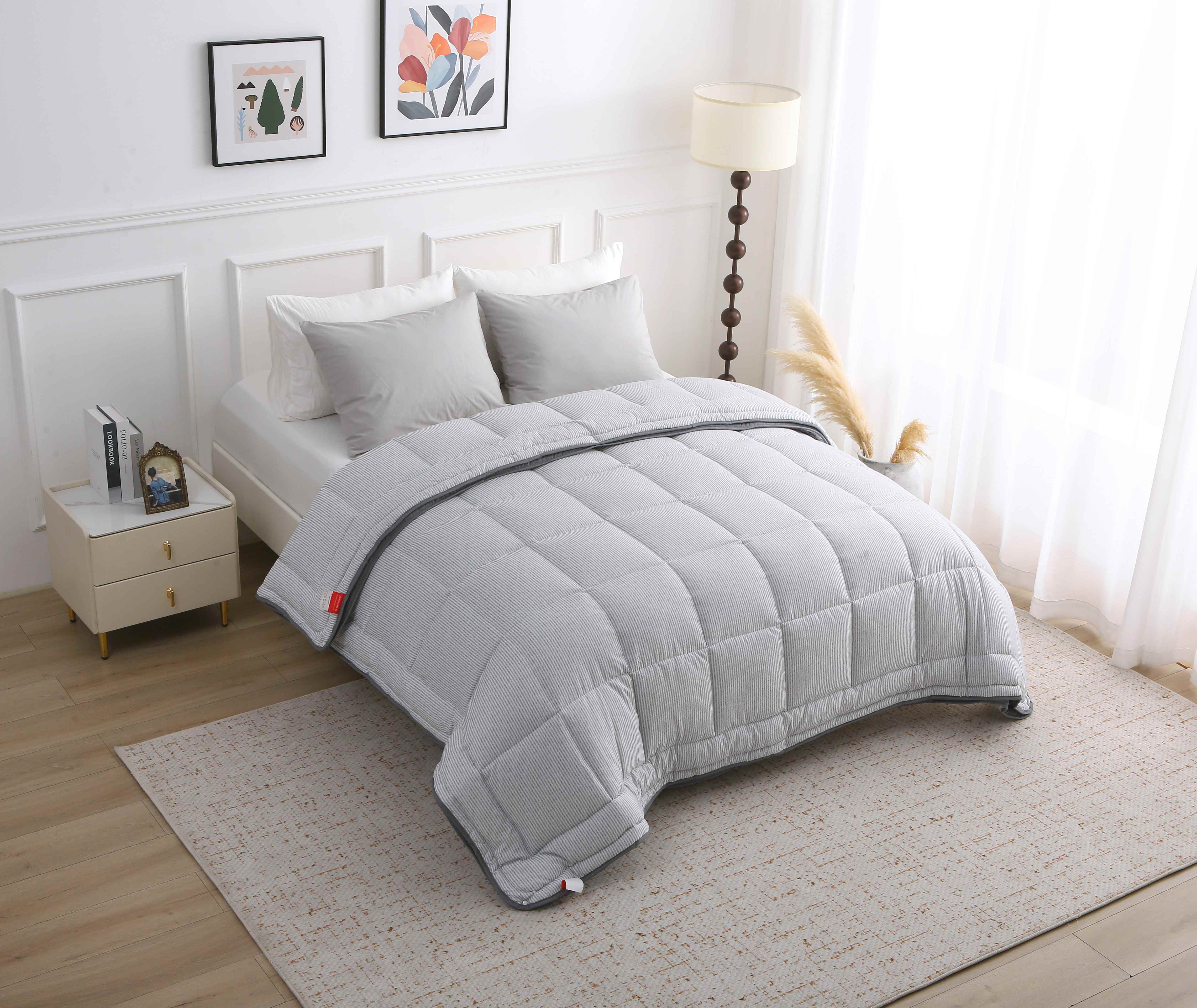 Overzicht van een stijlvol grijs gestreept 4-seizoenen dekbed zonder overtrek op een opgemaakt bed in een lichte slaapkamer
