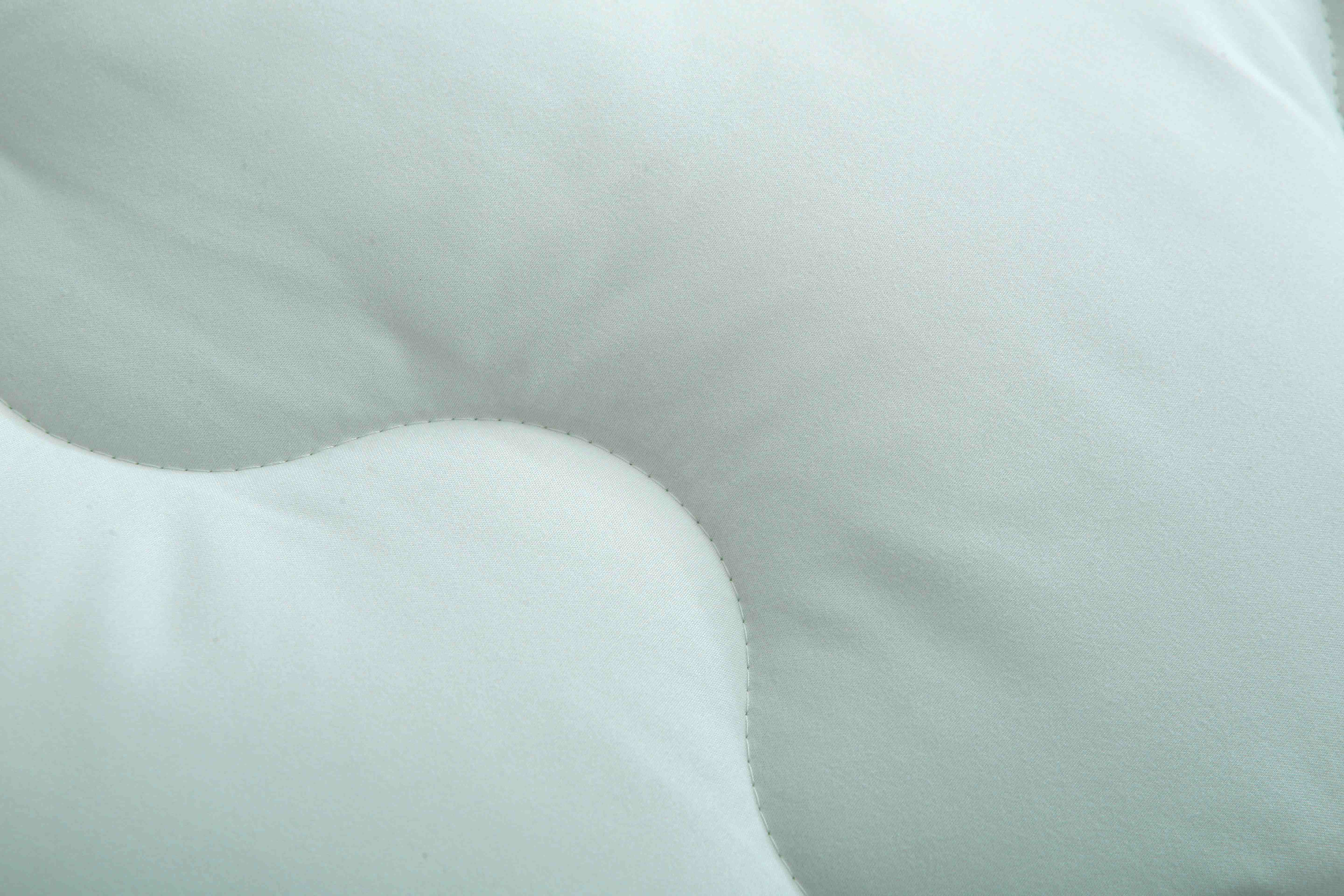 Detail van het stiksel van een lichtgroen dekbed zonder overtrek met ademende polyester vulling