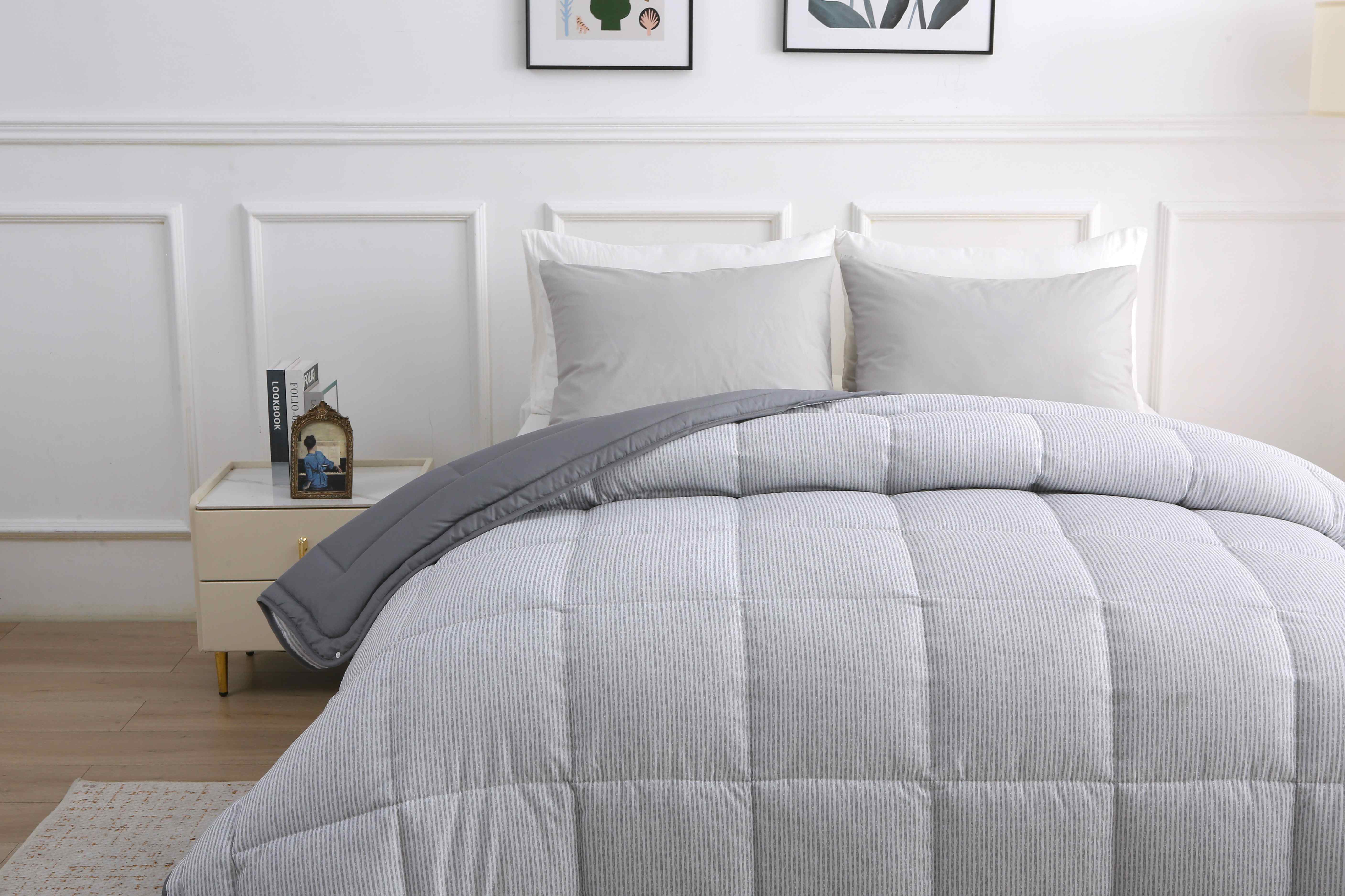 Zijaanzicht van een opgemaakt bed met 4-seizoenen dekbed met grijs gestreepte vaste hoes