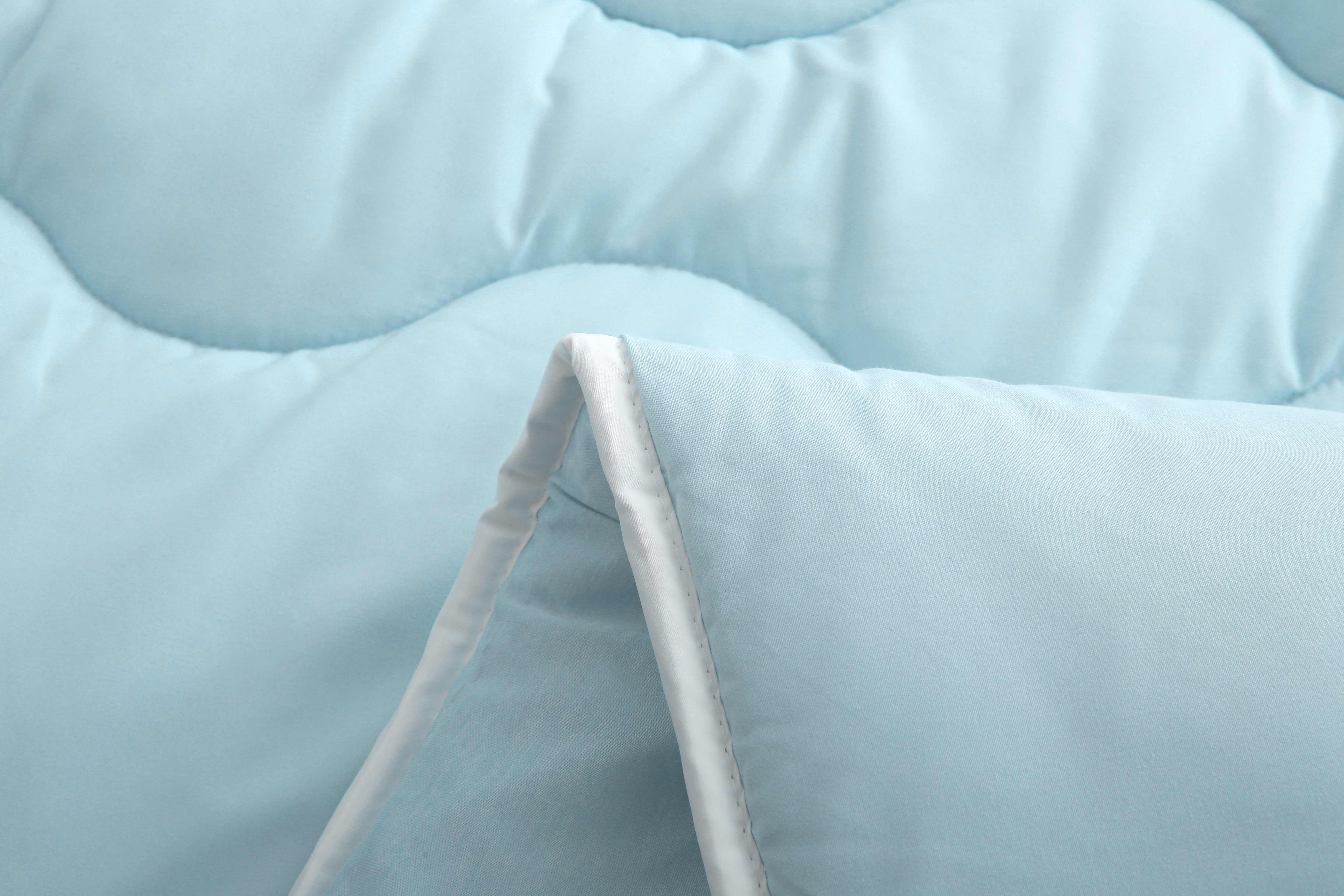 Detail van de rand van blauw dekbed met vaste hoes en verkoelend effect