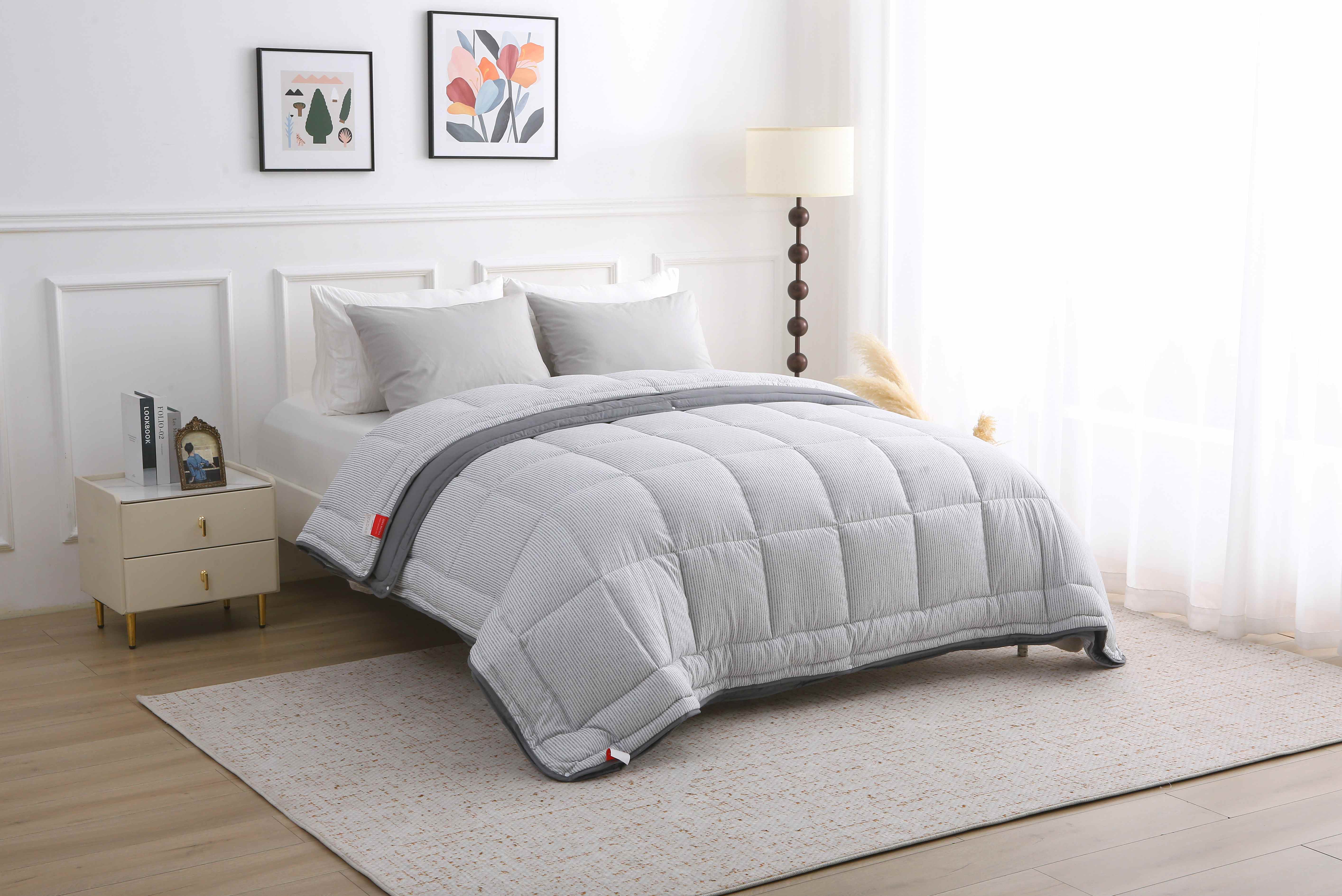 Tijdloze slaapkamer met lichtinval en een opgemaakt 4-seizoenen dekbed in grijs dessin zonder overtrek