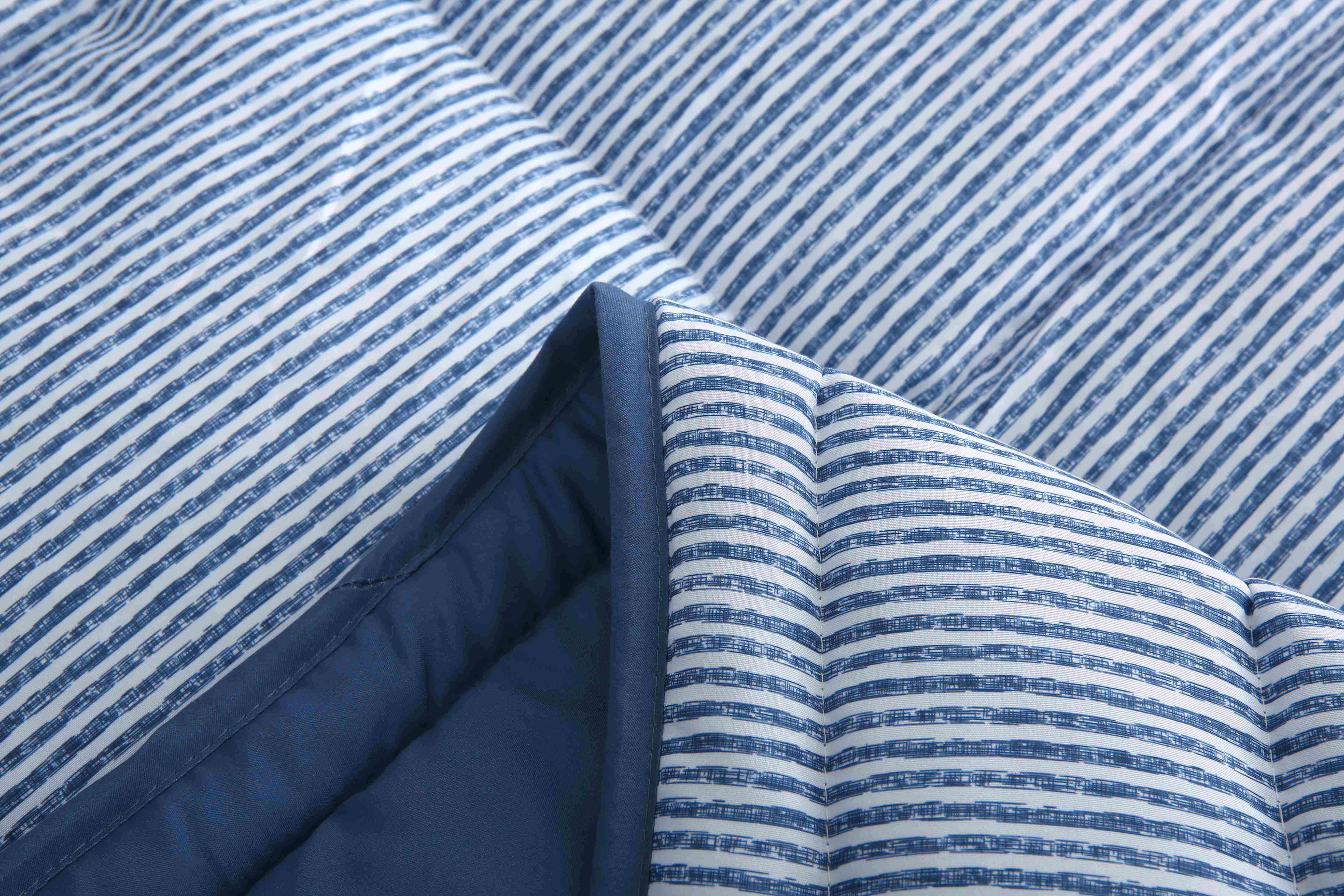 Close up van 4-seizoenen dekbed blauw gestreept, met zicht op effen gekleurde binnenkant