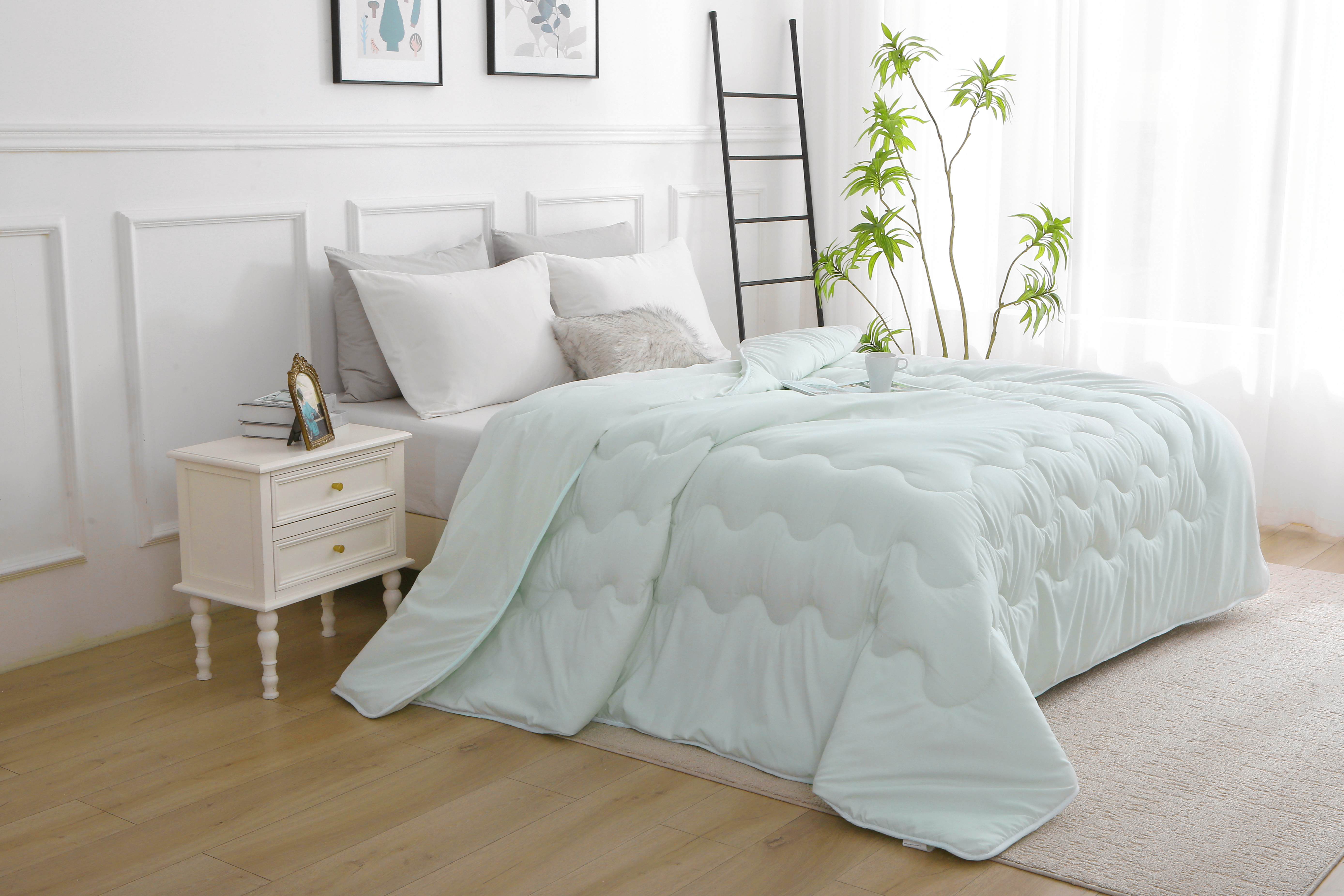 Lichtgroen dekbed zonder overtrek opgemaakt op bed in moderne slaapkamer