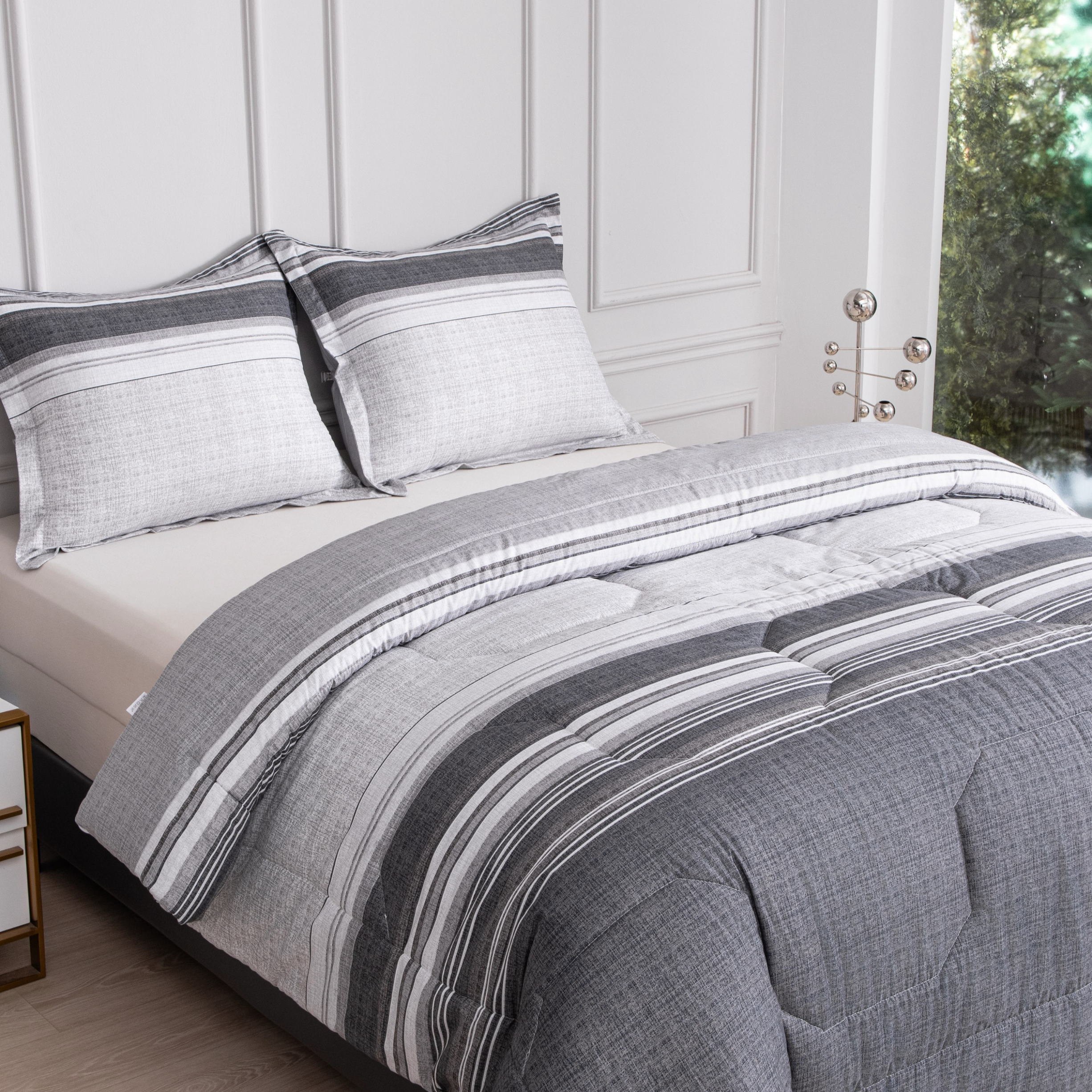 Diagonaal vooraanzicht van het Velvet dekbed in wit-grijze tinten met kussens