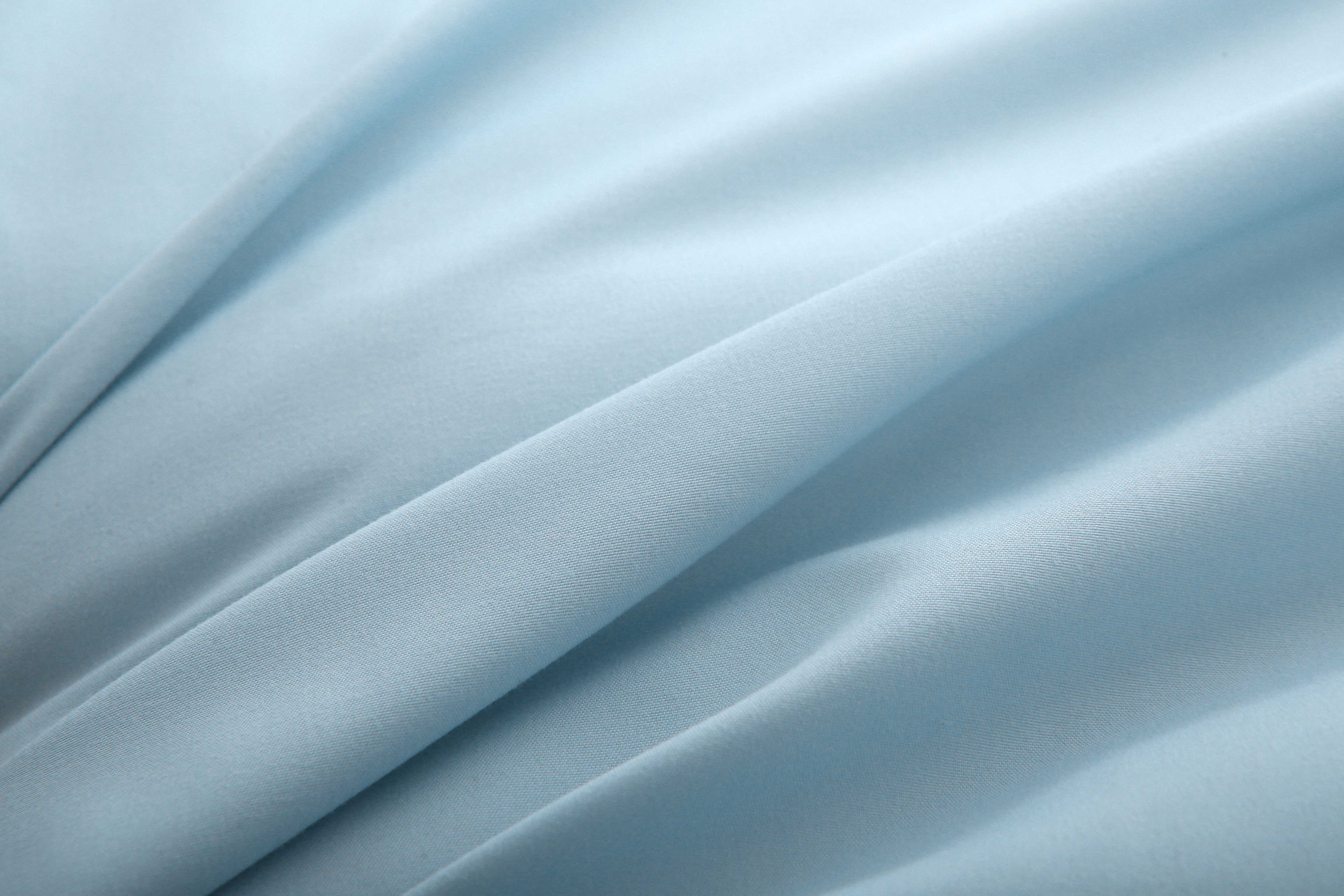 Close-up van zachte blauwe koelzijde van hoesloos zomerdekbed, gladde stofstructuur