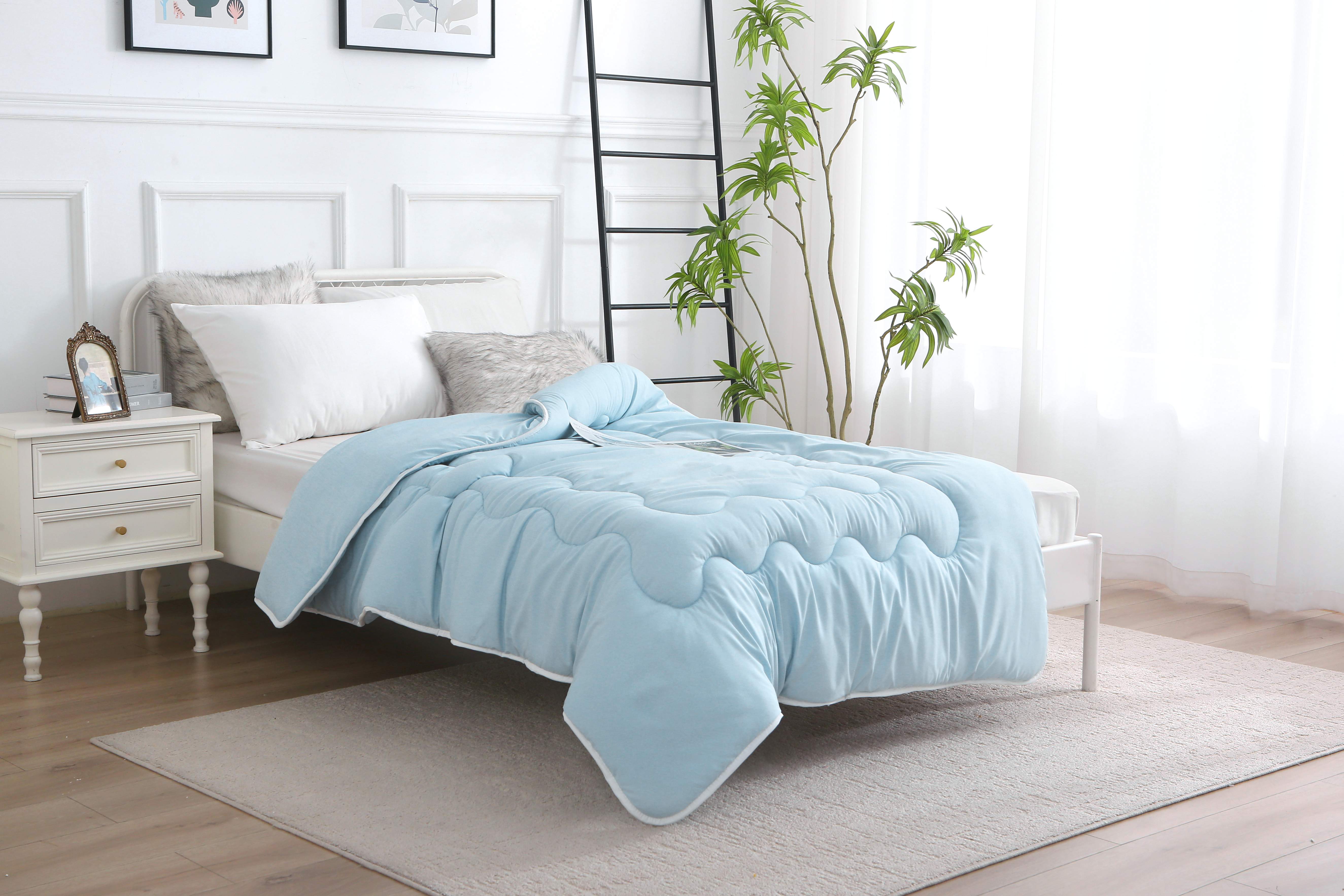 Blauw verkoelend zomerdekbed zonder overtrek, licht en ademend, op bed in lichte slaapkamer