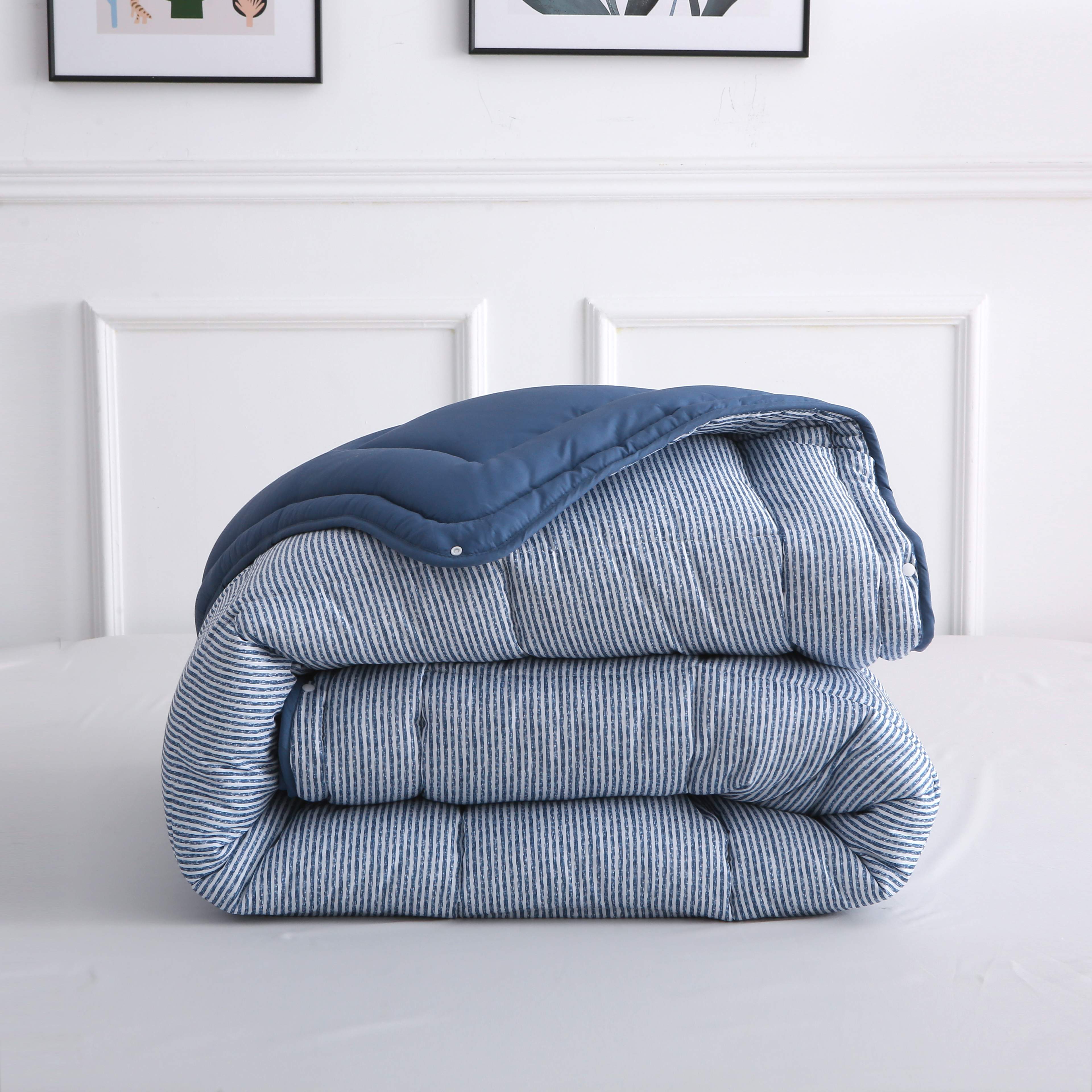 Opgevouwen blauw-wit gestreept 4-seizoenen dekbed zonder overtrek, toont compacte opvouwbaarheid en strakke afwerking – ideaal voor elk seizoen